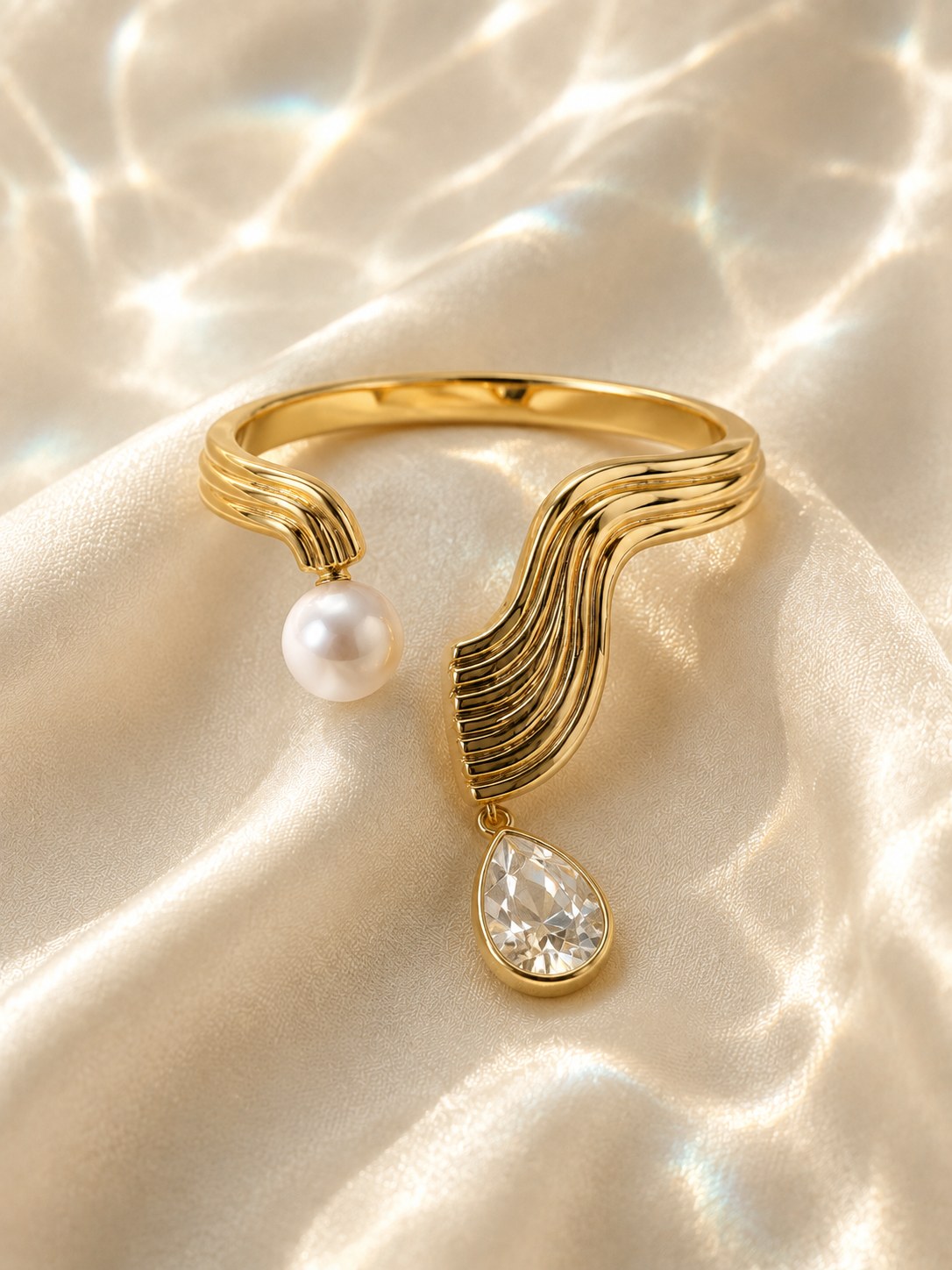 Mawj ring in gold with a pearl and a pear-cut diamond on water-lit satin