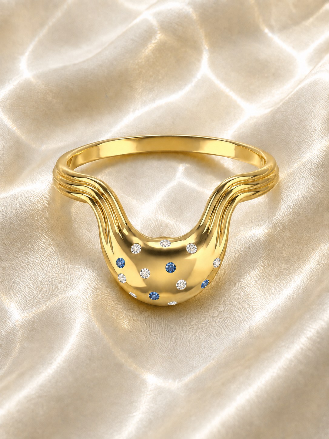 Mawj ring in gold with blue and white diamonds on water-lit satin